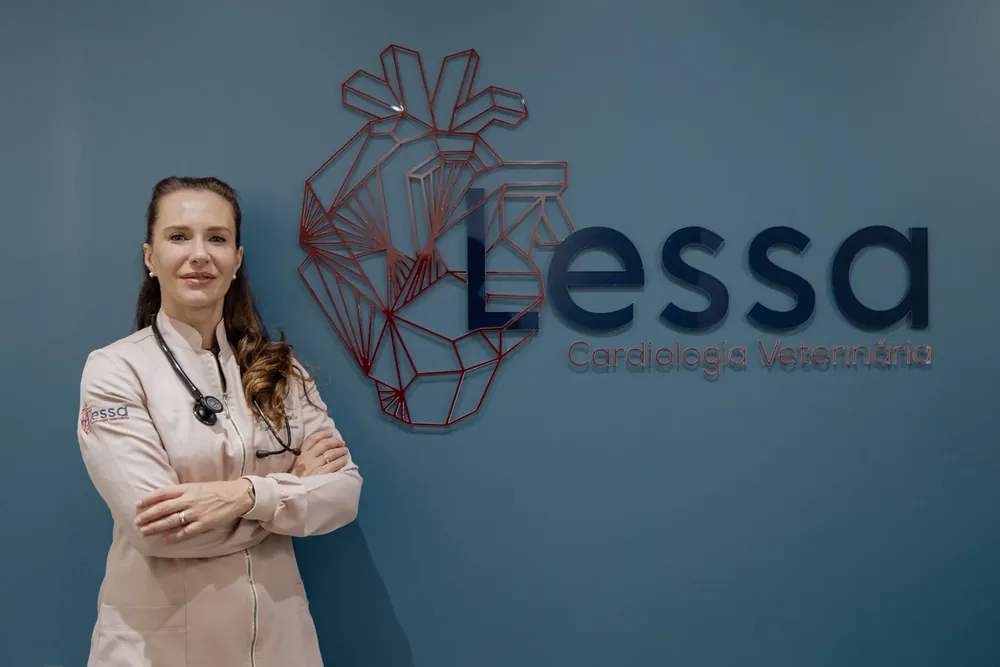 Veterinária da Lessa diante da parede com o logo da clínica